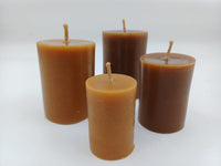Four smooth handmade beeswax pillar candles of different heights